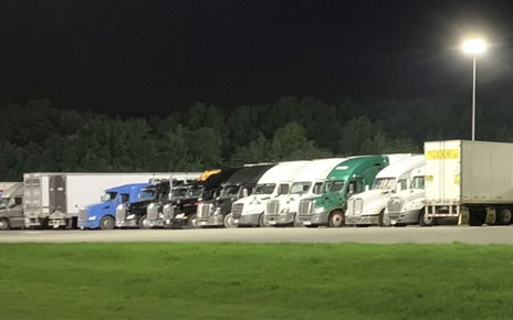 Parked freight trucks in a row at night.
