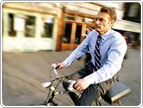 man in shirt and tie riding on a bicycle with his briefcase