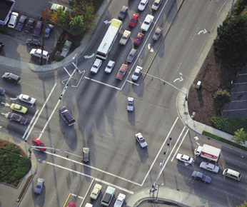 Aerial photograph showing a four-way intersection. Many vehicles are seen attempting to navigate the intersection at both of the cross-streets that meet at the intersection.