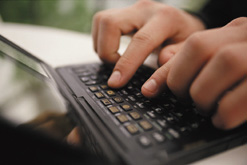 photograph showing two hands typing on a laptop keyboard.