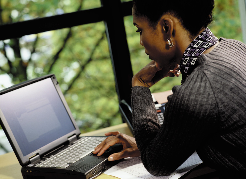 Photograph showing a woman working on a laptop computer.
