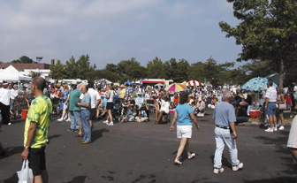 Photograph showing a crowd of people walking around a special event in a parking lot.