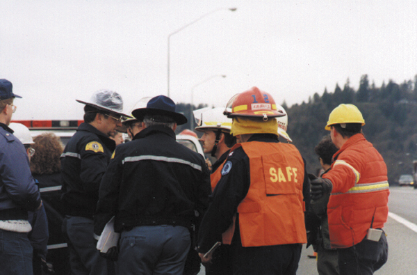 Photograph showing responders conferring with each other at the scene of a crash.