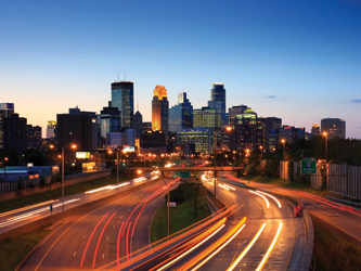 Cover graphic shows a view of the Minneapolis skyline under low ambient light conditions in the background. Light streaks in the foreground indicate motion on the highways to and away from the city.