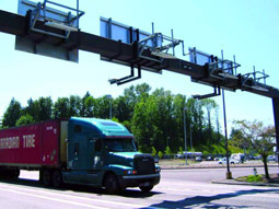 Photo of a truck passing under overhead signs containing sensors.