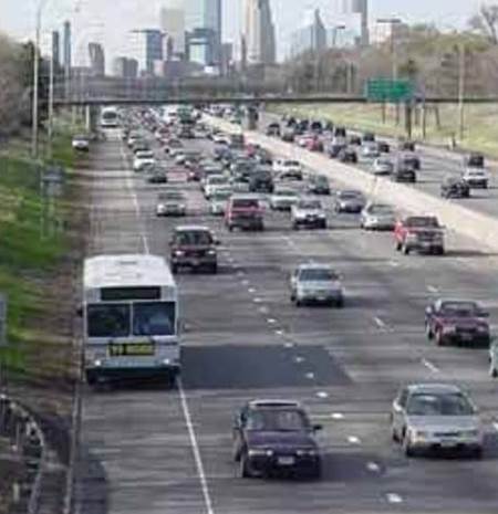 Photo shows cars and buses traveling on a busy urban freeway.