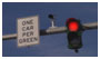 Photograph. A sign saying “One Car per Green,” a camera, and a traffic signal represent “traffic control devices.”