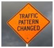 Photograph. An orange diamond-shaped road sign stating “Traffic Pattern Changed” represents “traffic patterns change.”