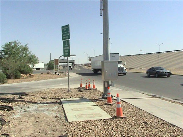 Figure 27. Photo. Power cabinet and in-ground battery installed at El Paso, US. This photo shows hardware installed on the El Paso side, specifically a power cabinet and in-ground battery located near the roadway.