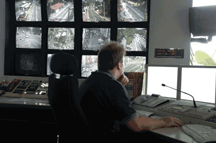 Picture of a transportation management center operator sitting at a console with a video wall in the background.