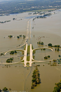 Aerial photo of a flooded plain in which an interstate runs. The water is so deep that only the cloverleaf ramps are visible.