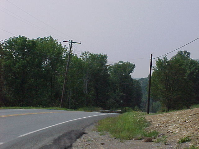 photo of roadway with almost level grassy bank on the right