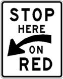 Graphic: STOP HERE ON RED road sign with white background and black outside border and text.  Below the words STOP HERE and above the words ON RED appears an arrow that is pointed down and to the left.  The words STOP and RED are the same size and slightly larger than the words HERE and ON, which are also the same size.