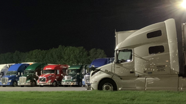 Trucks parked at truck stop at night.