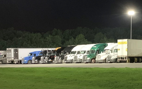 Row of freight trucks parked at night.