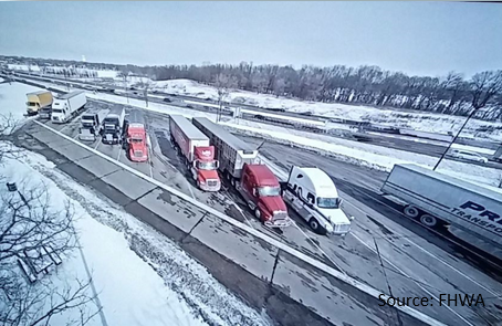 Row of freight trucks parked at a rest stop viewed from overhead.