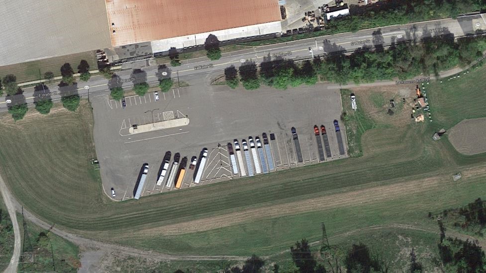 Aerial photo of a municipal truck parking lot in Elmira, NY with some trucks parked diagonally and some straight.