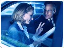 man and woman talking over papers in a car