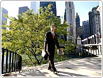 man in suit walking in park with skyscrapers in background