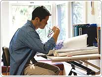 man sitting at desk looking over blueprints