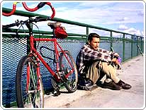 man sitting next to his bike leaned up against a rail
