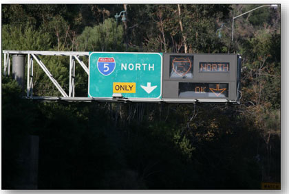 Photograph of the dynamic junction control signing used in Los Angeles.  The sign structure has a green guide sign on the left showing an exit only to I-5 North and a dynamic message sign on the right showing that the shoulder of the ramp is open to exit I-5 North.
