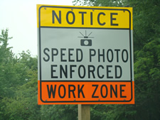 A sign with text "Notice" with yellow background, below that text "Speed Photo Enforced" with grey background, and below that text "Work Zone" with orange backgroud.
