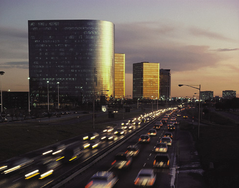 Photograph showing vehicles traveling in both directions on a congested highway in the evening. 