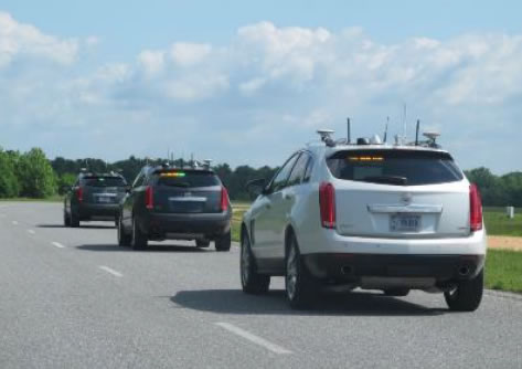 An image of three cars with antennas and equipment on the roof of the cars driving on a road.