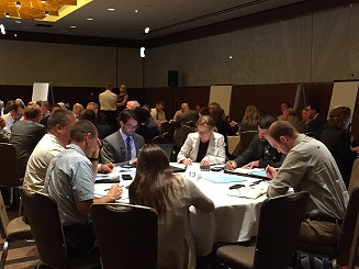 Image of a small group Session explored several questions related to automation and freight operations, including the biggest challenges and opportunities, considerations for roadway design, impacts on bridges, routing and truck size and weight. Participants are sitting around tables.