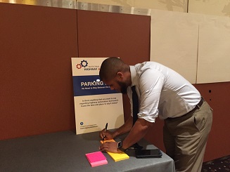 Image of Federal Highway Administration Team Leader for Transportation Planning and Capacity Building, James Garland, facilitated the "Parking Lot" station for the Collaboration Corner session at a display table.
