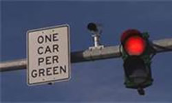 Picture of a red signal indication with adjacent sign "One Car Per Green".