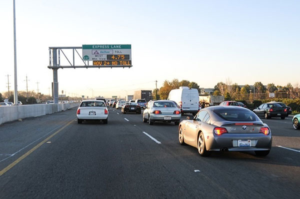 Photograph of the SR 237/I-880 Express Lanes in Santa Clara County, California.  The photo shows the southbound lanes of the I-880 Interstate, as it approaches SR 237.  A changeable message signs is shown on the left side of the image with a toll rate of $4.75 and a text message of 'HOV2+ NO TOLL' on the bottom of the sign.