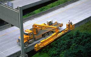 Figure 7-1 H3 Hawaii Inspection of Elevated Section: a highway department truck with a large boom lowers workers over the side of the bridge
