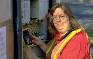 Figure 7-5 Fiber-Optic Testing, Norfolk, Virginia: a female employee uses testing equipment to test fiber optic lines