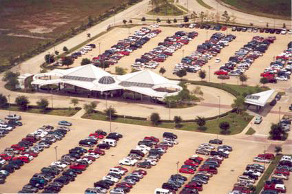 Figure 7: This photo illustrates the Fuqua park-and-ride lot and transit station located along the Gulf (I-45S) Freeway in Houston.  It shows automobiles parked in the lot and a large covered structure where people wait for buses.  This figure helps the reader understand the design and operation of the park-and-ride lots associated with the Houston HOV lanes.