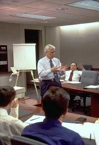 Figure 5-3 Training Underway: a gentleman speaks in front of a boardroom of people