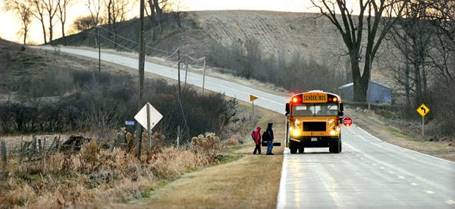 School bus picking up two kids on rural road.