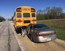 Car has crashed into back school bus.  Front of car is damaged.