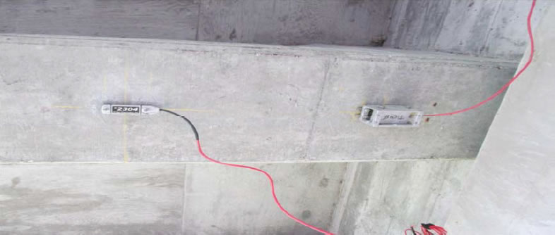 Figure 1 showing strain transducer and rotation sensor near girder end.  Devices are mounted on girder with red electrical wires coming from them.