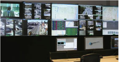 Image of Philadelphia Traffic Operation Center.  Several Video screens are on the wall with tables and chairs facing the wall screens.
