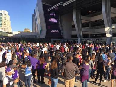 Large group of people wearing a lot of purple in front of stadium