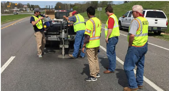 Several UA and ALDOT men in the middle of a traffic lane drilling a hole.