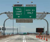 Photo. Overhead signs identifying 'Toll Lane Only' and 'HOV 2+ Only' lanes in Denver, Colorado.