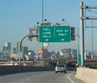 Photo. Overhead signs identifying 'Toll Lane Only' and 'HOV 2+ Only' lanes and vehciles using the lanes in Denver, Colorado.