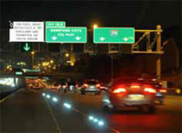 Photo. Overhead signs identifying toll lane along I-35W in Minneapolis, Minnesota at nighttime.