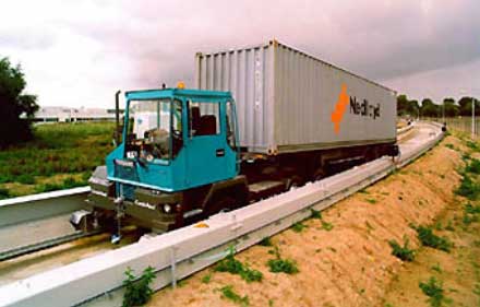 photo of a driverless truck with its frame riding on a track of two parallel rails: a guideway