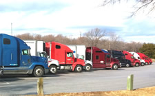 Various tractor trailers lined up at a truck parking area.