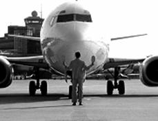 Front view of an airplane and an airport crew member directing the plane.