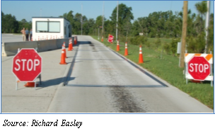 Photograph of the entry to a static scale deployment weigh station. Stop signs are at both sides of the entry and orange cones align both sides of the road. Source: Richard Easley.